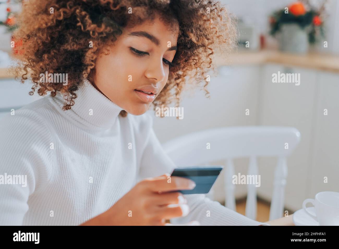 Lady avec la peau parfaite sombre tenant la carte de crédit et l'insertion des informations bancaires pour les achats en ligne se trouve près de l'ordinateur portable de près Banque D'Images