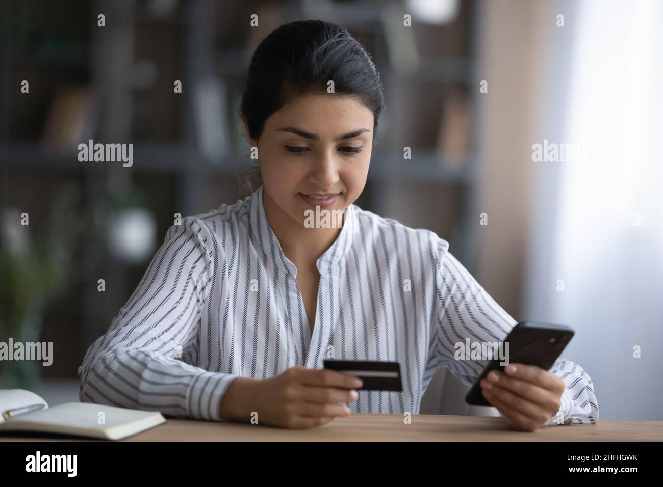 Bonne jeune femme indienne magasiner sur Internet. Banque D'Images