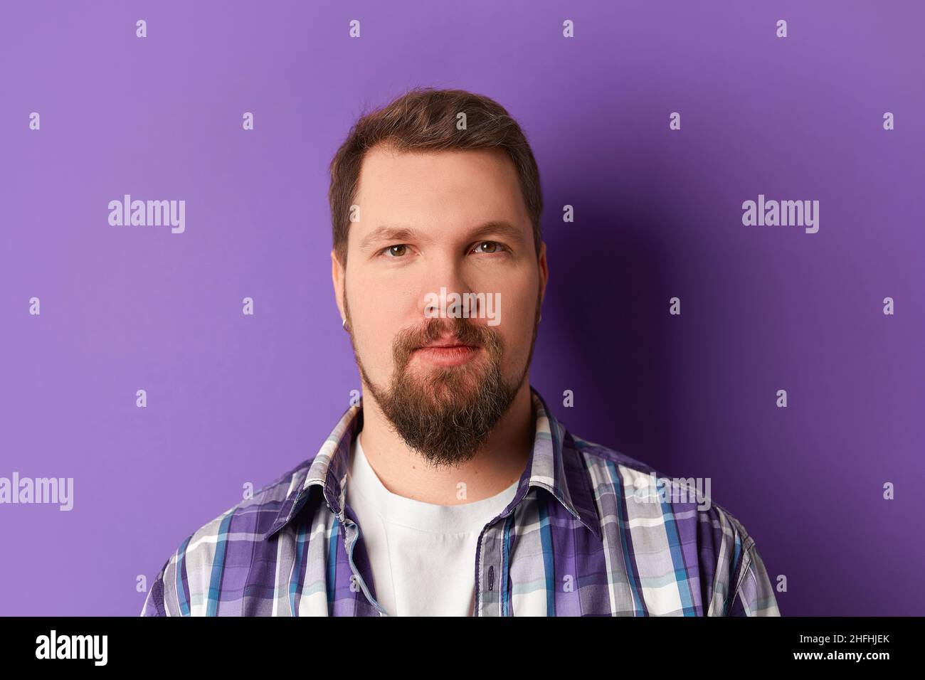 Joyeux barbu homme en chemise souriant regardant l'appareil photo sur fond violet.Jeune homme élégant et charmant Banque D'Images