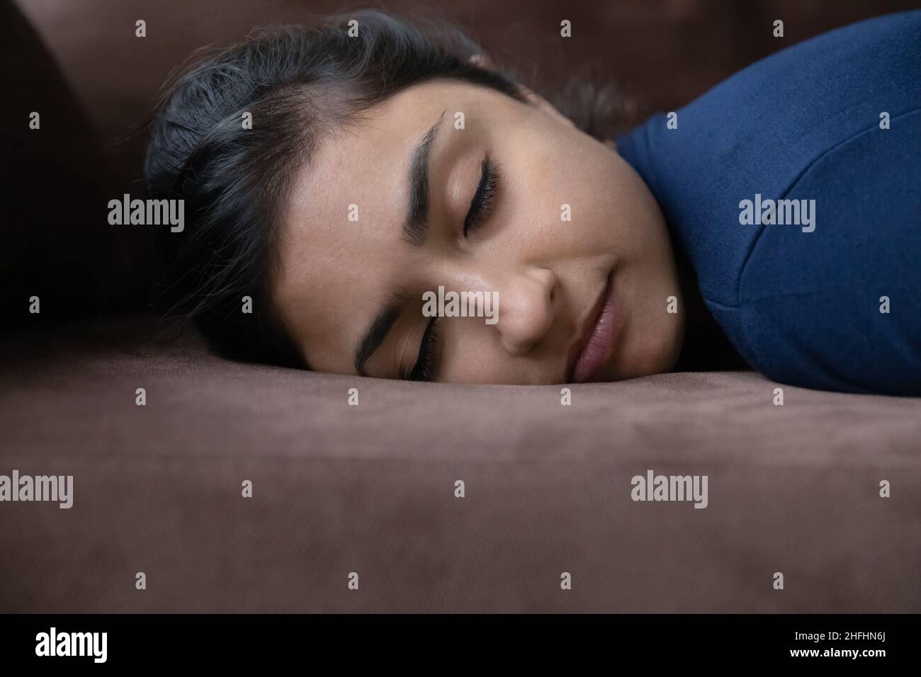 Une jeune femme indienne fatiguée dormant sur un canapé. Banque D'Images
