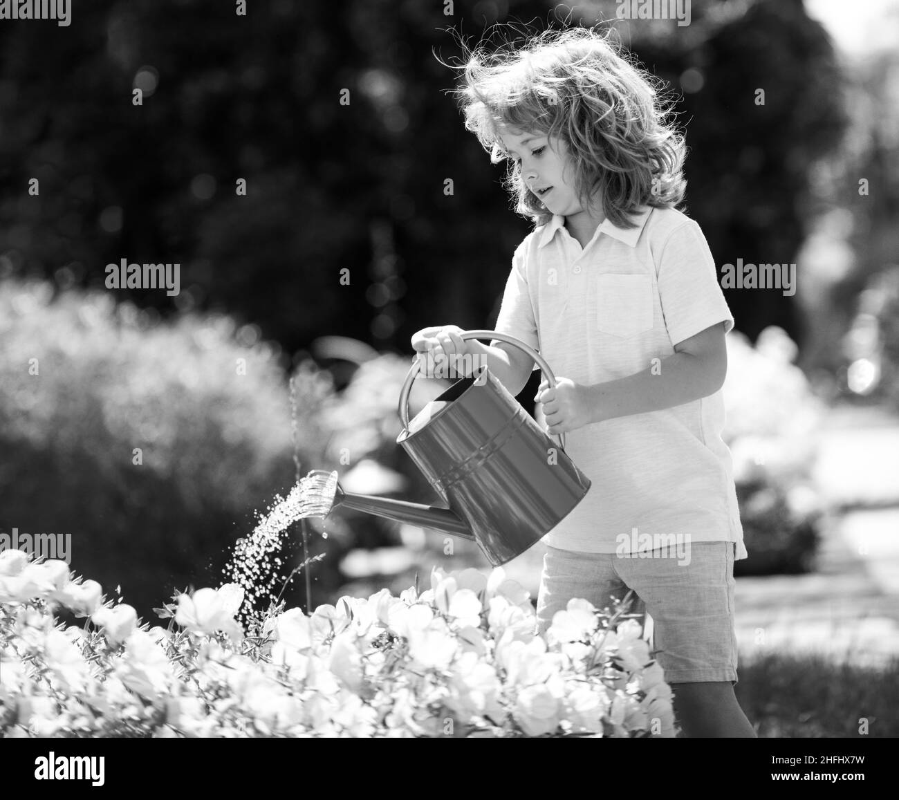 Adorable petit garçon enfant arrosoir fleurs avec arrosoir. Jardinage pour enfants. Banque D'Images