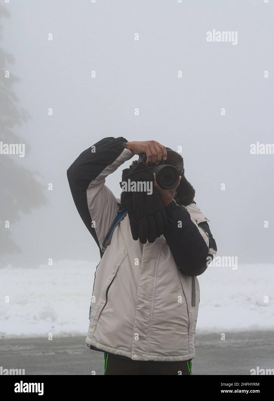 Photographe dans la neige d'hiver faisant des photos de la nature et capturant la faune et les paysages.Vue sur la rue, photo de voyage, mise au point sélective. Banque D'Images