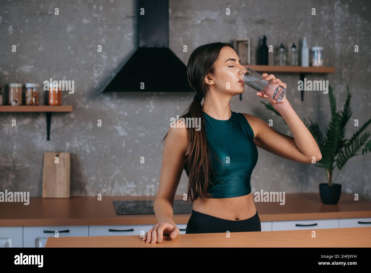 Femme caucasienne debout dans la cuisine à la maison boire de l'eau douce après avoir fait l'entraînement.Régime, mode de vie sain, concept de perte de poids.Concept de beauté Banque D'Images