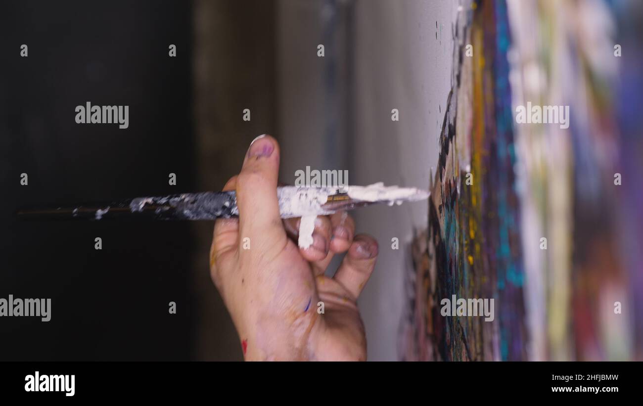 Un artiste designer dessine un aigle sur le mur.Artisan décorateur peint une image avec de l'huile acrylique couleur.Gros plan, magie et obscurité, aspect cinématographique. Banque D'Images