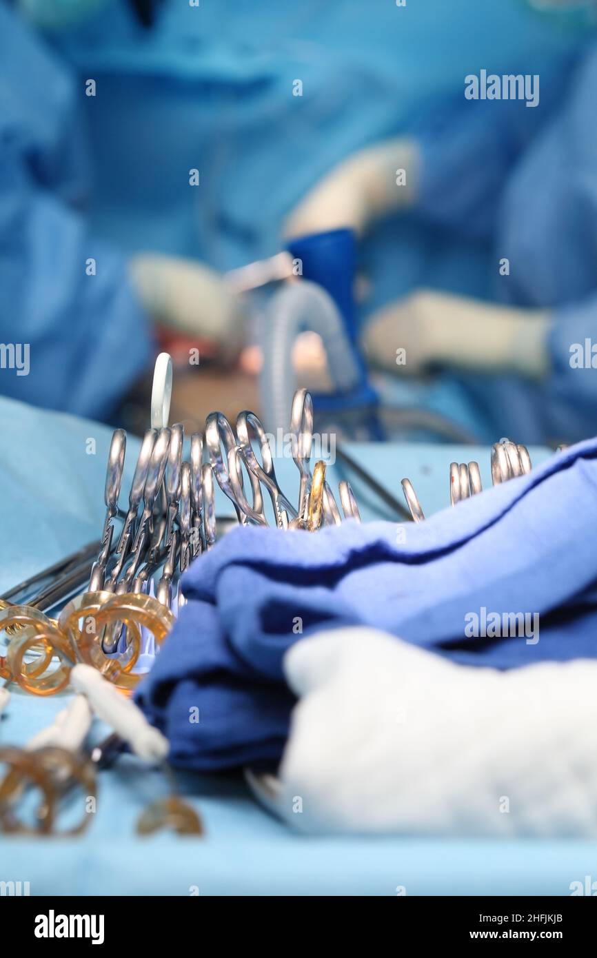 Instruments chirurgicaux brillants sur la table stérile sur le fond des chirurgiens se sont concentrés sur leur travail. Banque D'Images