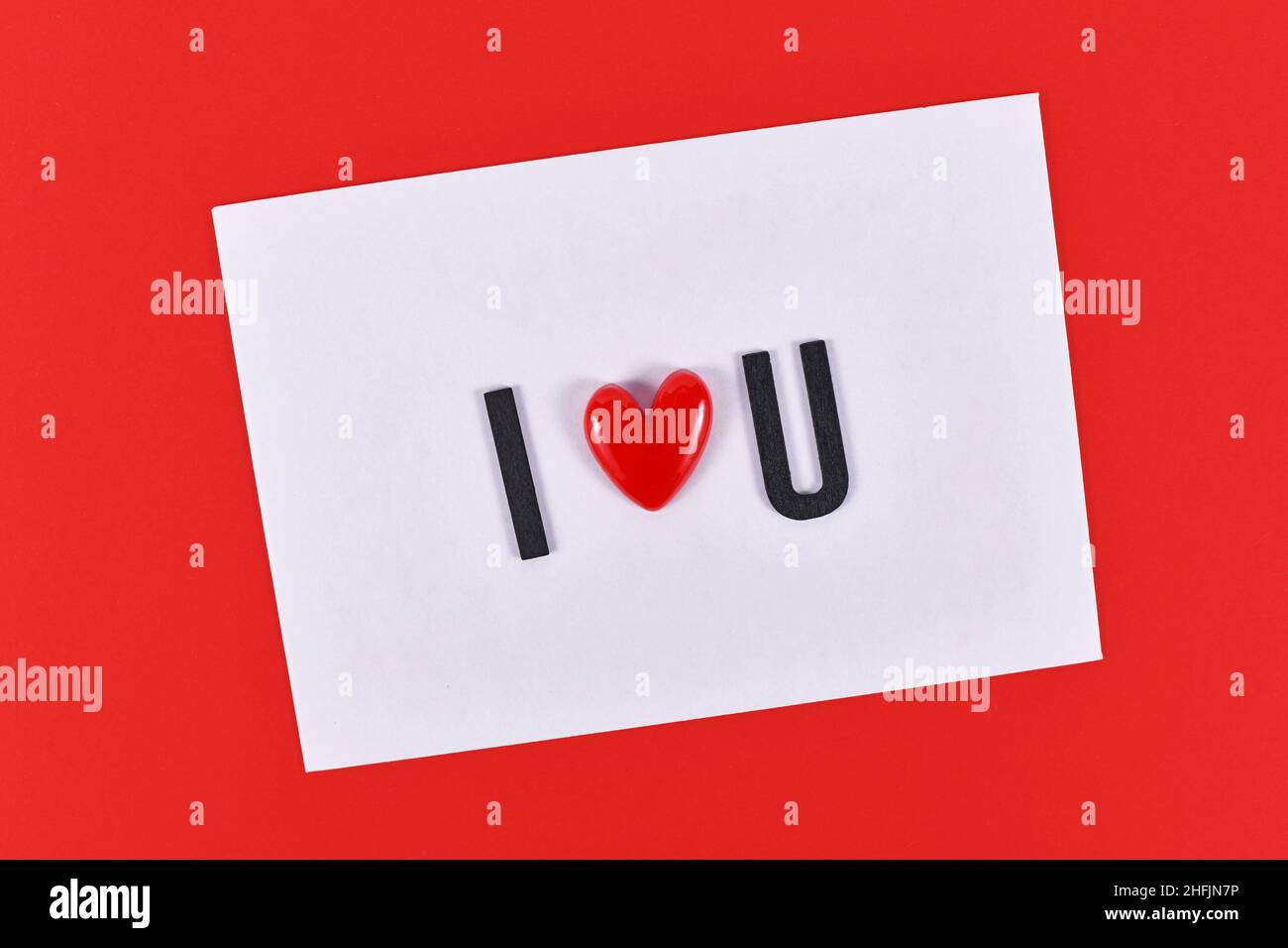 Texte de la Saint-Valentin « I love You » écrit en lettres cœur sur une carte blanche sur fond rouge Banque D'Images