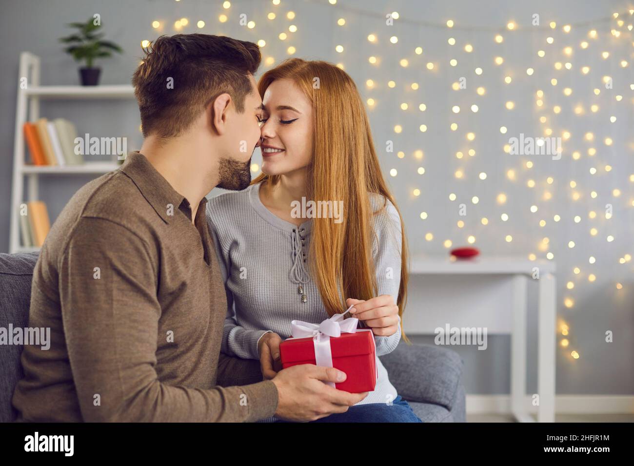 Un jeune couple affectueux s'embrasse pendant les cadeaux et les fêtes à la maison Banque D'Images