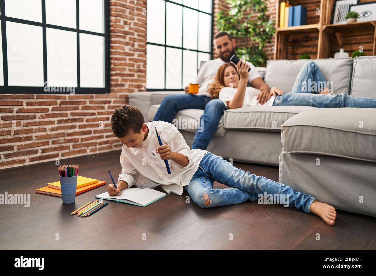 Famille regardant la télévision et fils dessinant sur un ordinateur portable à la maison Banque D'Images