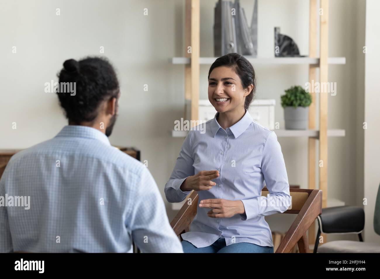 Femme indienne souriante pratiquant la langue des signes avec un ami. Banque D'Images