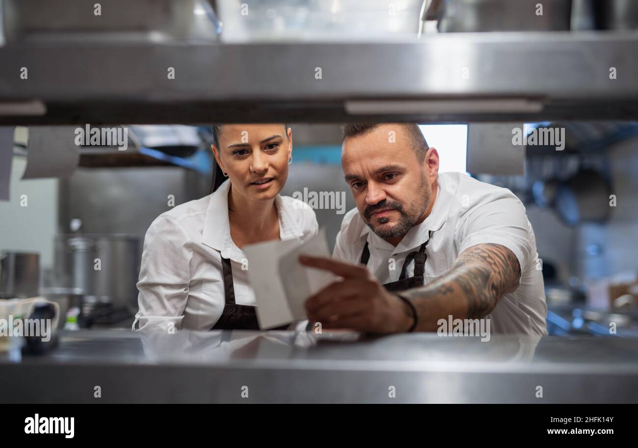 Chef et cuisinier prenant la fiche de commande dans la cuisine commerciale. Banque D'Images