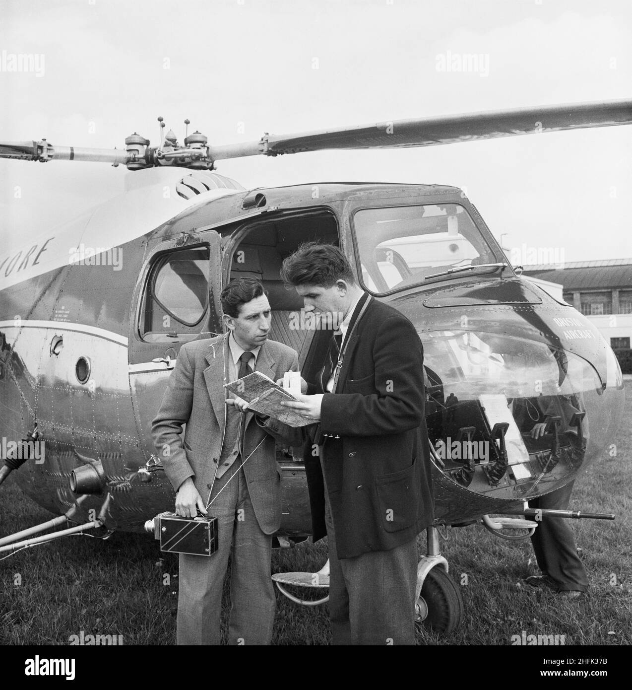 Filton Airfield, South Gloucestershire, 04/04/1957.Deux hommes, l'un tenant une caméra, se concertant sur des cartes à côté d'un hélicoptère à l'aérodrome de Filton.L'hélicoptère de ce photographe peut être un Bristol Sycamore, construit par la Bristol Airplane Company. Banque D'Images