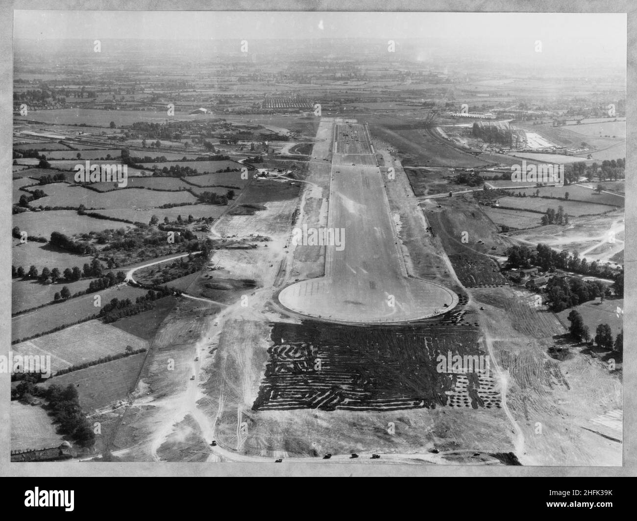 Filton Airfield, South Gloucestershire, 01/09/1947.Vue aérienne de l'ouest montrant la construction d'une nouvelle piste à l'aérodrome de Filton.Laing a prolongé la piste vers l'ouest à l'aérodrome de Filton pour accueillir le Bristol Brabazon, qui était en cours de construction à l'aérodrome.Les travaux ont commencé en juillet 1946 sur la nouvelle piste, qui avait une longueur de 2 725 mètres et une largeur de 100 mètres.Les travaux ont nécessité la réquisition et l'enlèvement du village de Charlton et une bande volante temporaire a été posée, pour être utilisée pendant la construction de la nouvelle piste.Le négatif de cette impression a été numérisé et catalogué dans le cadre de Banque D'Images