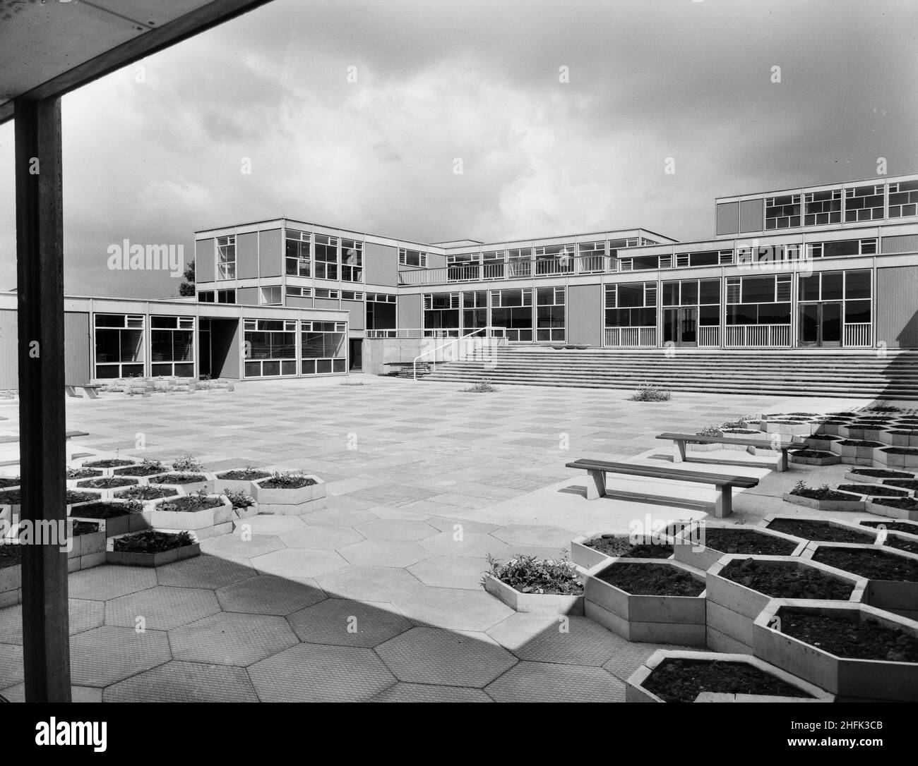 County High School, Gedling Road, Arnold, Gedling, Notinghamshire,29/07/1959.La cour principale de l'Arnold County High School, vue depuis le coin sud-est, montre un revêtement hexagonal et des parterres de fleurs surélevées au premier plan.Les travaux ont commencé sur le site en mars 1958 et les travaux de construction ont été achevés pour la nouvelle période scolaire en septembre 1959.L'école de grammaire co-éducative a accueilli 720 élèves.Au milieu de 1960s, une autre école a été construite à proximité et, en 1974, les deux ont été fusionnées en une école complète.Les bâtiments scolaires construits par Laing ont finalement été démolis en 2017. Banque D'Images
