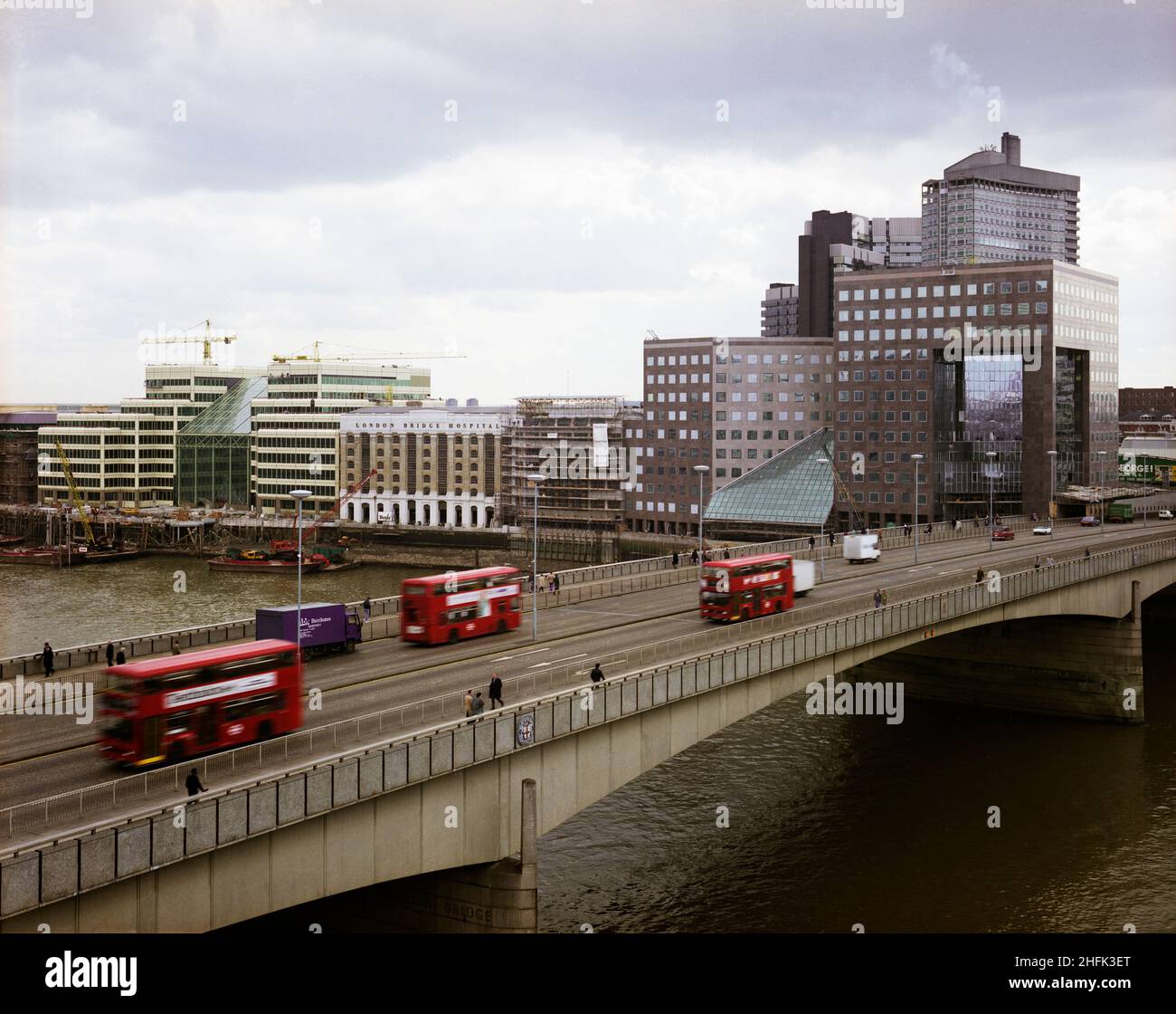 London Bridge City, Southwark, Greater London Authority, 01/04/1986.Vue sud-est sur le London Bridge et la Tamise en direction du London Bridge City Complex, montrant le pont n° 1 de Londres sur la droite.Divers bâtiments de ce complexe de bureaux, d'appartements et de boutiques sur la rue Tooley à London Bridge City ont été construits par Laing Management Contracting pour le groupe St Martins qui a redéveloppé l'ancien site Hay's Wharf sur la rive sud de la Tamise.Le réaménagement du site s'est déroulé sur une période de 2 1/2 ans entre 1985-1988 et comprenait le pont no 1 de London, Cottons, Hays Galleria et 29-33 Banque D'Images