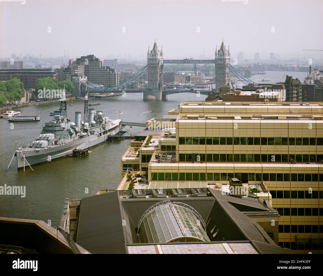 London Bridge City, Southwark, Greater London Authority, 19/06/1986.Vue vers l'est sur le complexe London Bridge City, montrant le HMS Belfast amarré sur la Tamise avec Tower Bridge au-delà.Divers bâtiments de ce complexe de bureaux, d'appartements et de boutiques sur la rue Tooley à London Bridge City ont été construits par Laing Management Contracting pour le groupe St Martins qui a redéveloppé l'ancien site Hay's Wharf sur la rive sud de la Tamise.Le réaménagement du site s'est déroulé sur 2 1/2 ans entre 1985-1988 et comprenait le pont no 1 de London, Cottons, Hays Galleria et 29-33 Banque D'Images