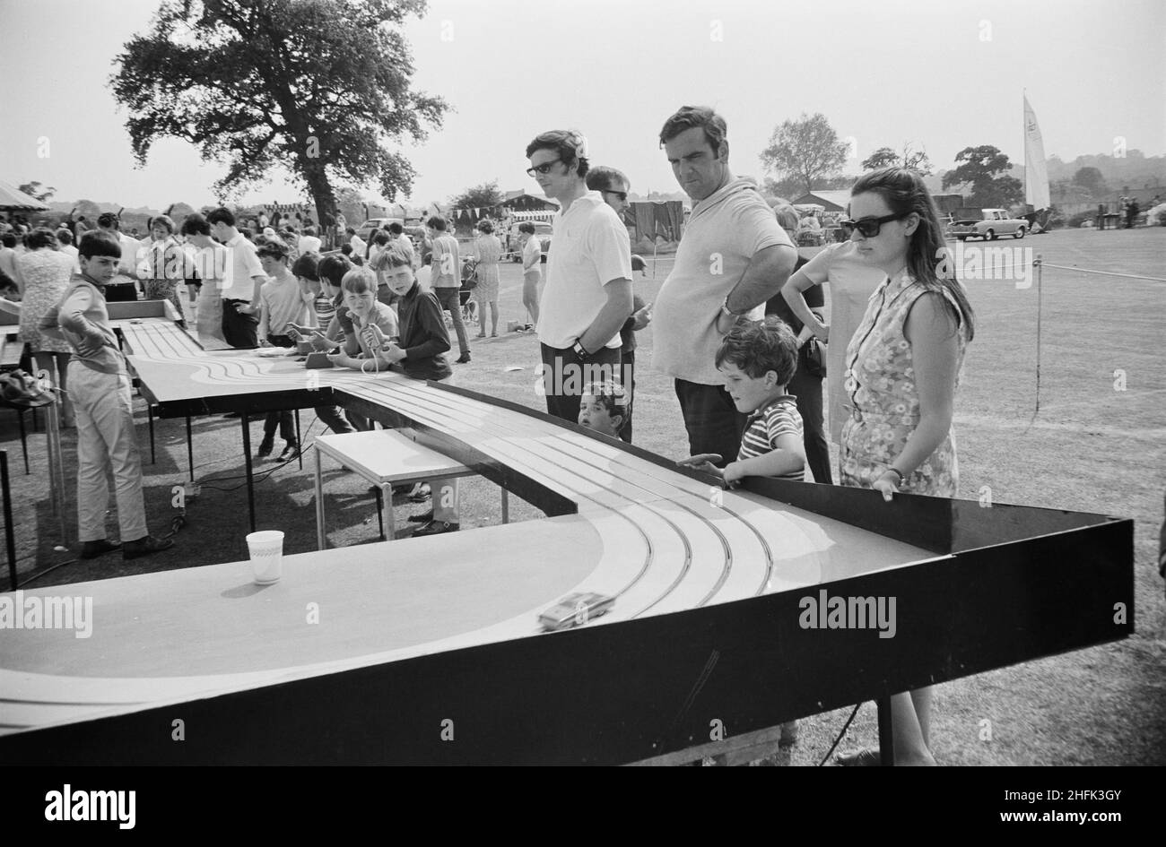 Laing Sports Ground, Rowley Lane, Elstree, Barnett, Londres,14/06/1969.Les adultes et les enfants regardent des voitures à sous se balader autour d'un circuit surélevé, les enfants faisant fonctionner des contrôleurs au-delà, lors d'une journée de gala qui s'est tenue au stade de Laing Sports à Elstree.Le 14th juin 1969, Laing a tenu une journée de gala au stade de Laing, en remplacement de la Journée annuelle des sports.Le club sportif a organisé des manifestations sportives, notamment des tournois de hockey, de tennis, de pétanque et de football.Un programme traditionnel anglais de fete a comporté des noix de coco, bingo, poney manèges, restauration et une tente de bière, la soie de bonbons, an Banque D'Images