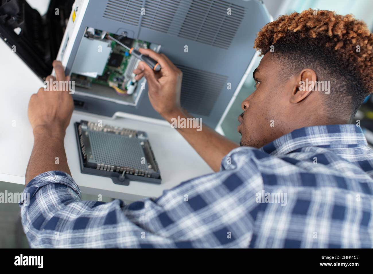 un homme est en cours de réparation sur le système d'alimentation en jet d'encre Banque D'Images