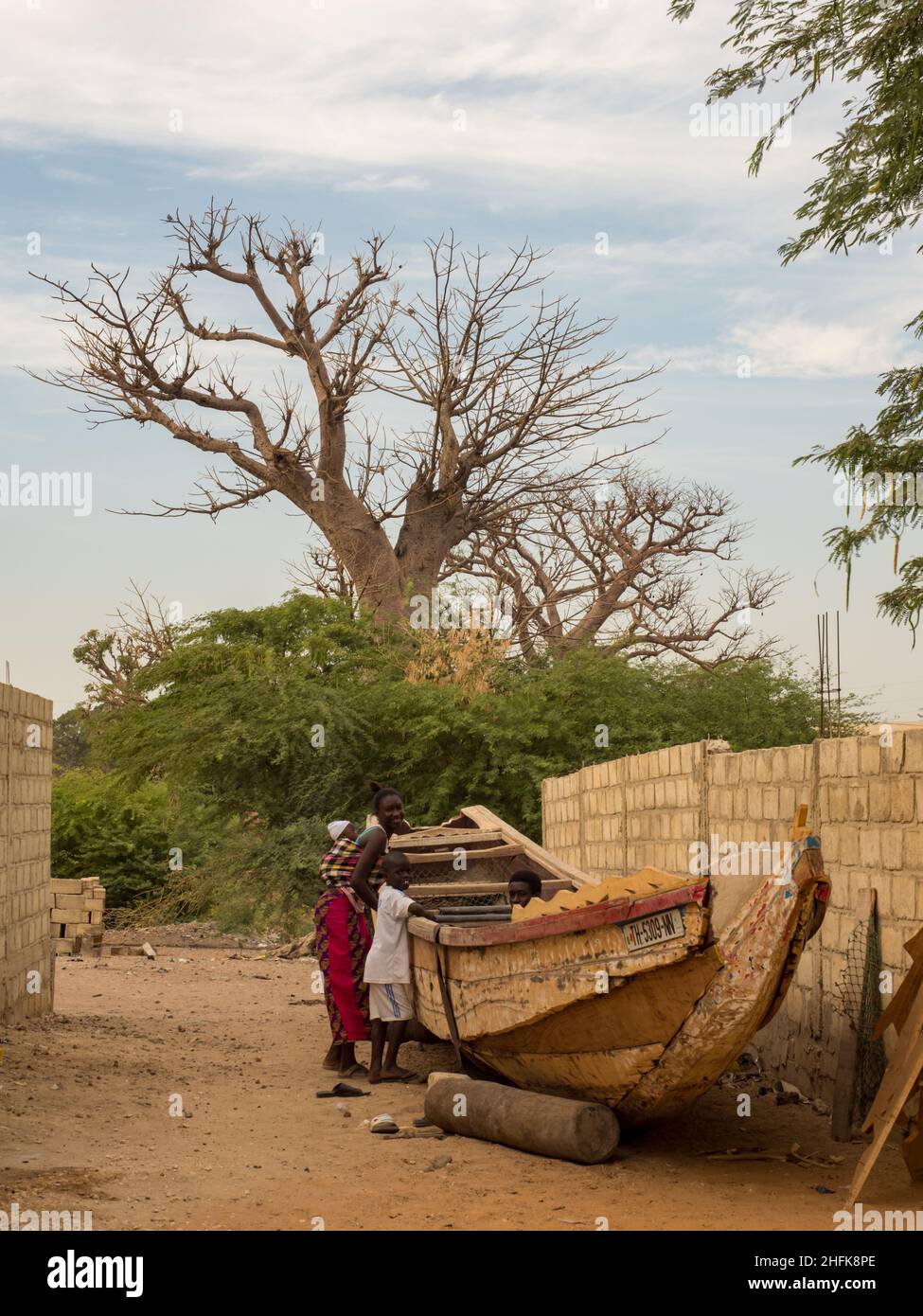 Sénégal, Afrique - 24 janvier 2019 : un énorme baobab et un bateau en bois sur la route rouge africaine.Arbre du bonheur, Sénégal.Afrique. Banque D'Images