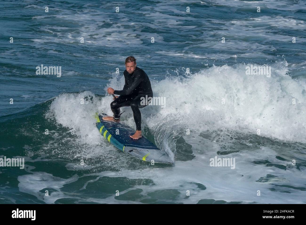Un Paddleboarder debout déterminé qui fait une vague à Fistral, à Newquay, dans les Cornouailles. Banque D'Images