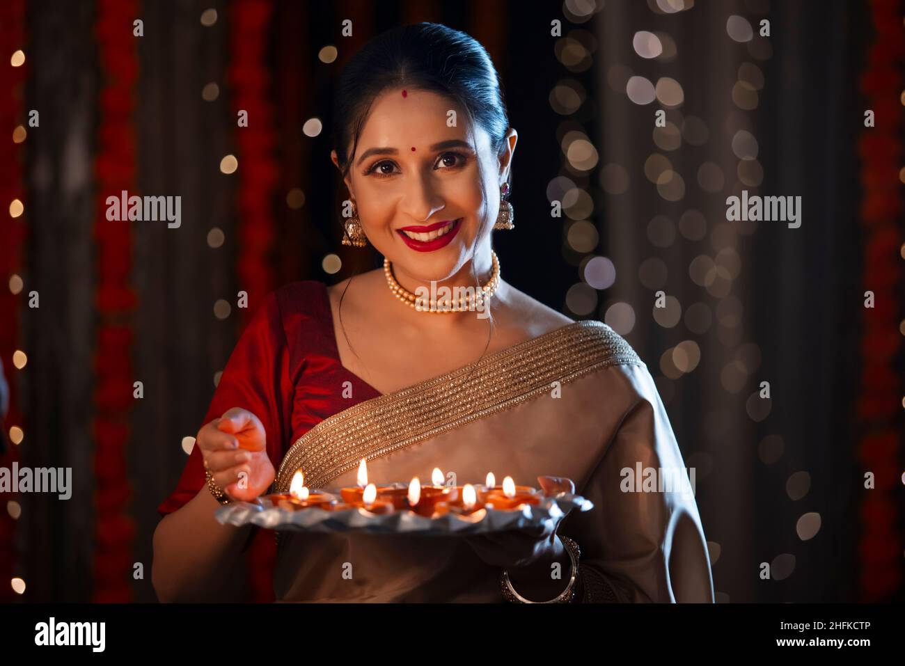 Femme indienne tenant un thali plein de diyas avec le sourire à l'occasion de Diwali Banque D'Images