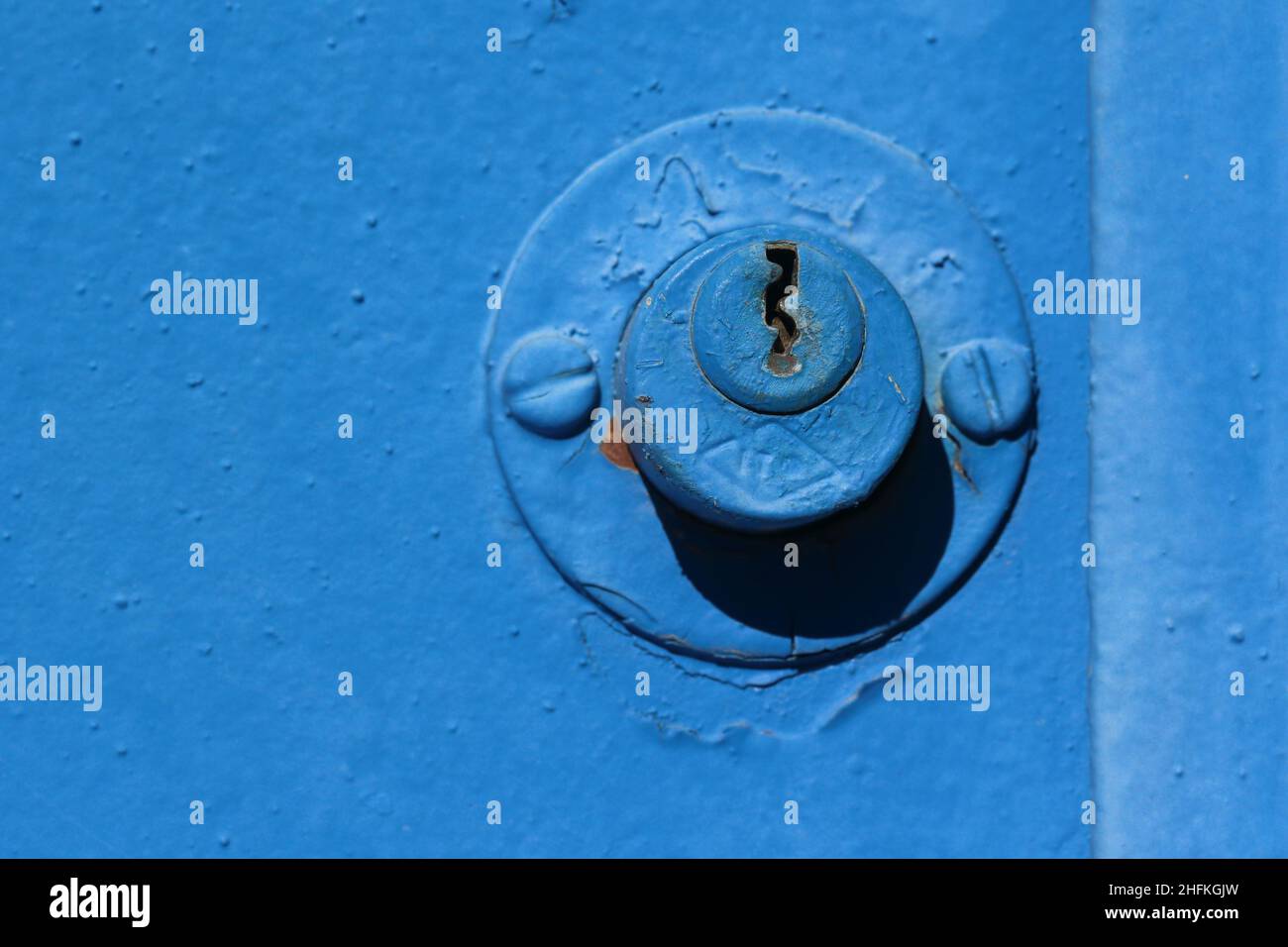 une vieille porte en métal bleu avec une serrure. Photo macro d'une porte en métal peinte en bleu avec une vieille serrure cylindrique et un trou de serrure Banque D'Images