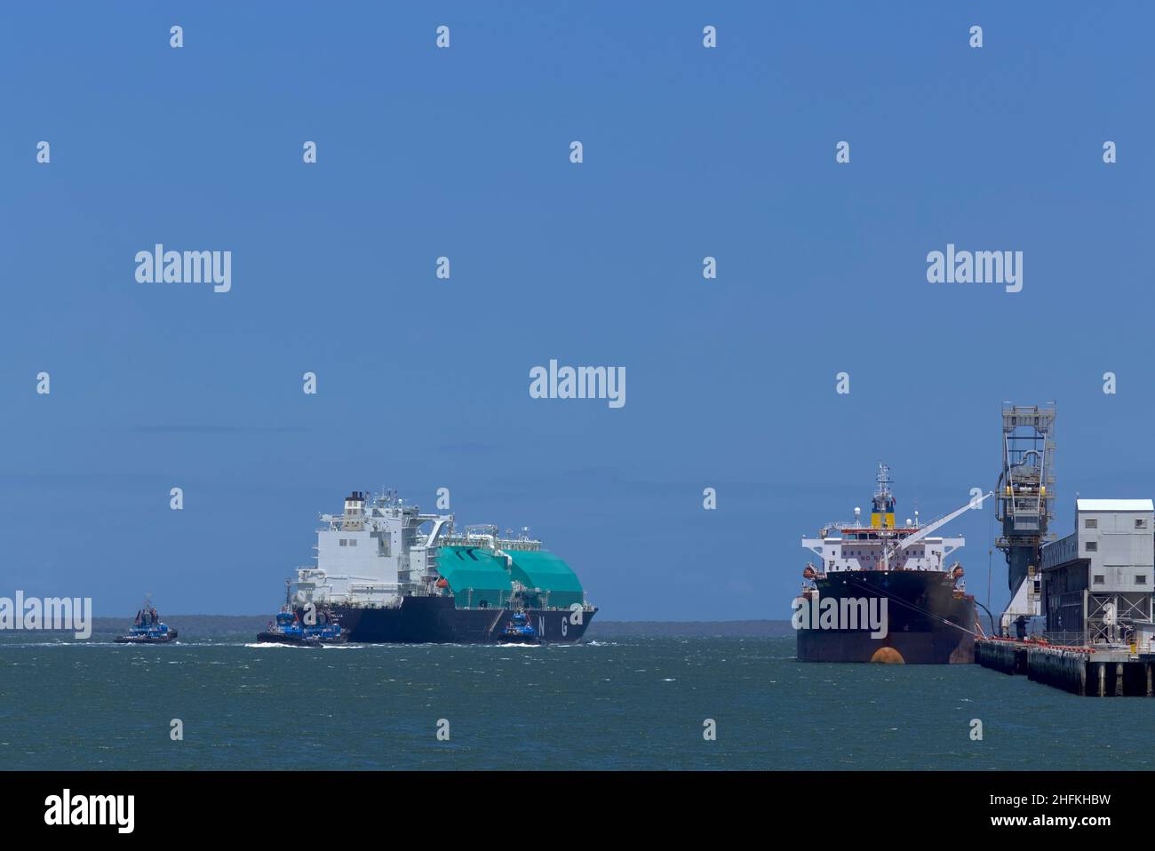 Navire-citerne à gaz naturel liquéfié (GNL) Seri Camellia, qui exporte depuis l'île Curtis Gladstone Queensland Australie, assisté de remorqueurs. Banque D'Images