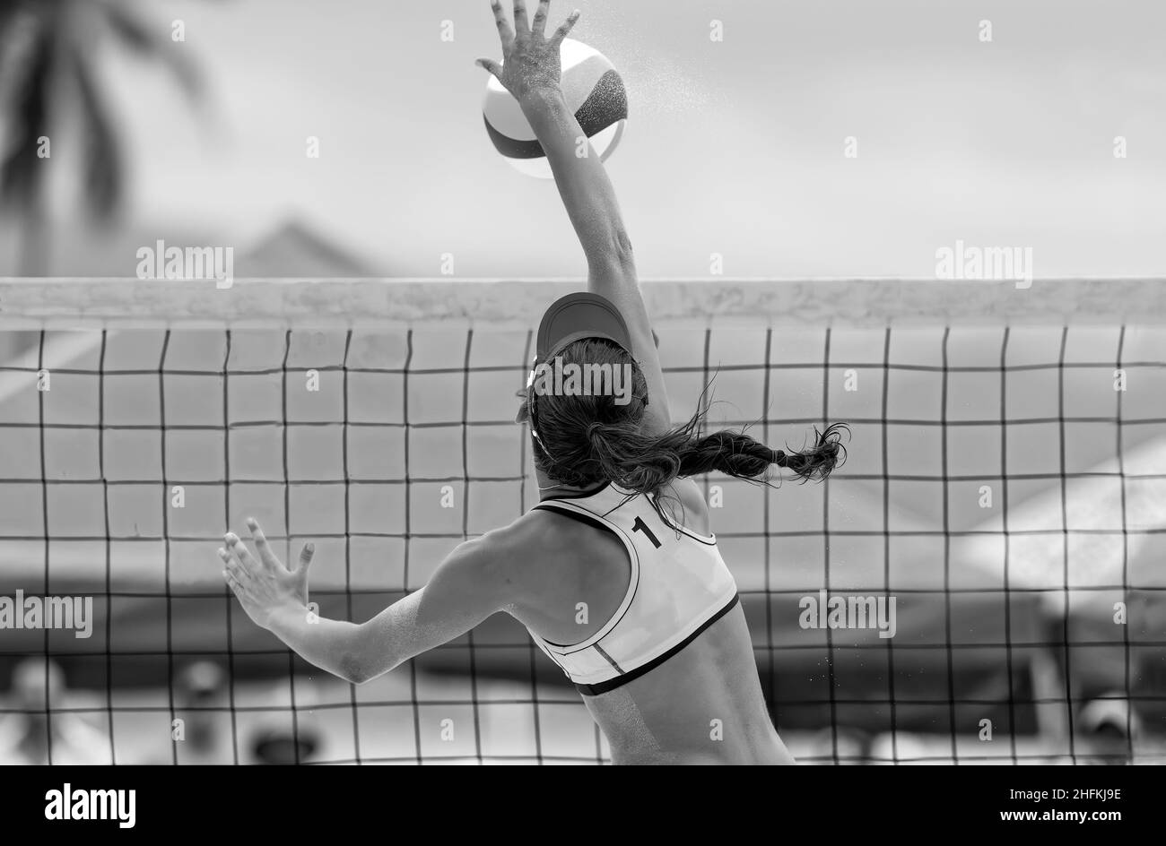Un joueur féminin de Beach volley monte sur le Net pour frapper le ballon le ballon en noir et blanc format d'image Banque D'Images