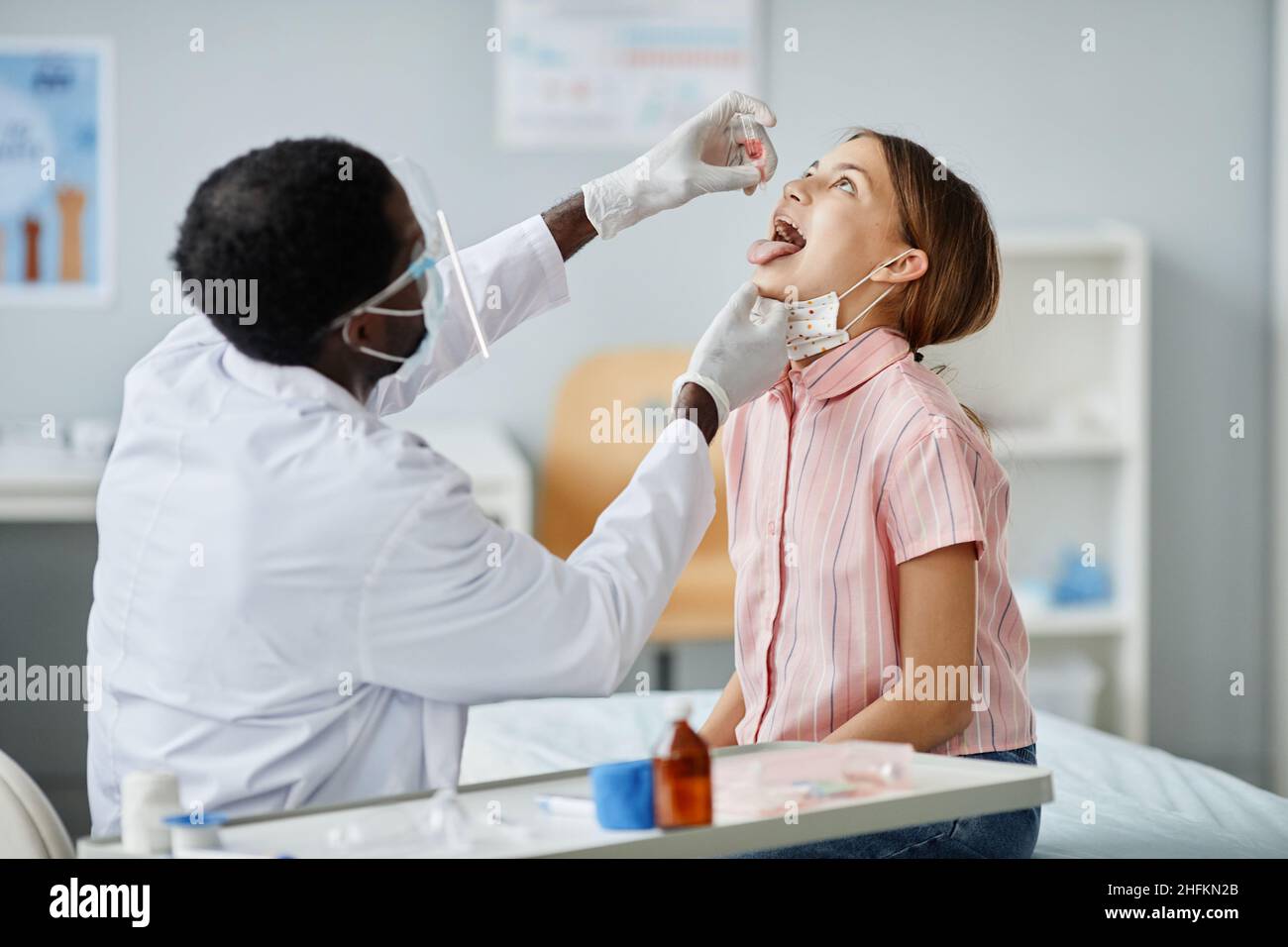 Portrait afro-américain d'un médecin qui dépose du liquide dans la bouche de l'enfant pendant la vaccination orale en clinique Banque D'Images