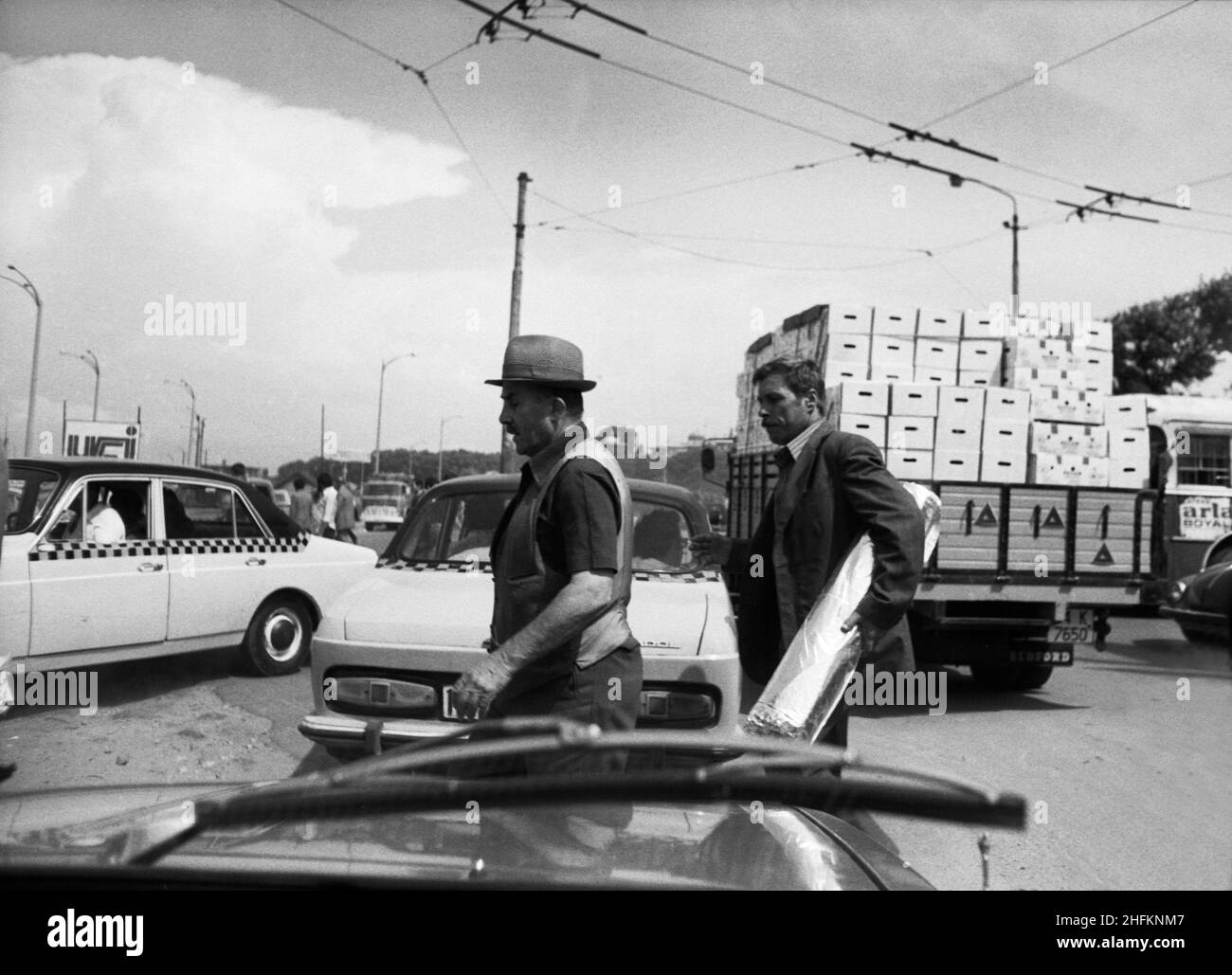 Les hommes traversent la rue entre les voitures.Istanbul, Turquie, 1979 Banque D'Images