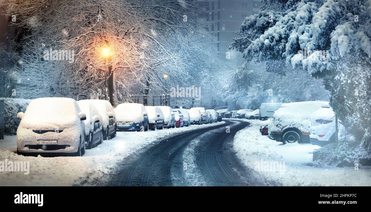 Scène urbaine d'hiver avec des voitures couvertes de neige garées alnog la rue au crépuscule Banque D'Images