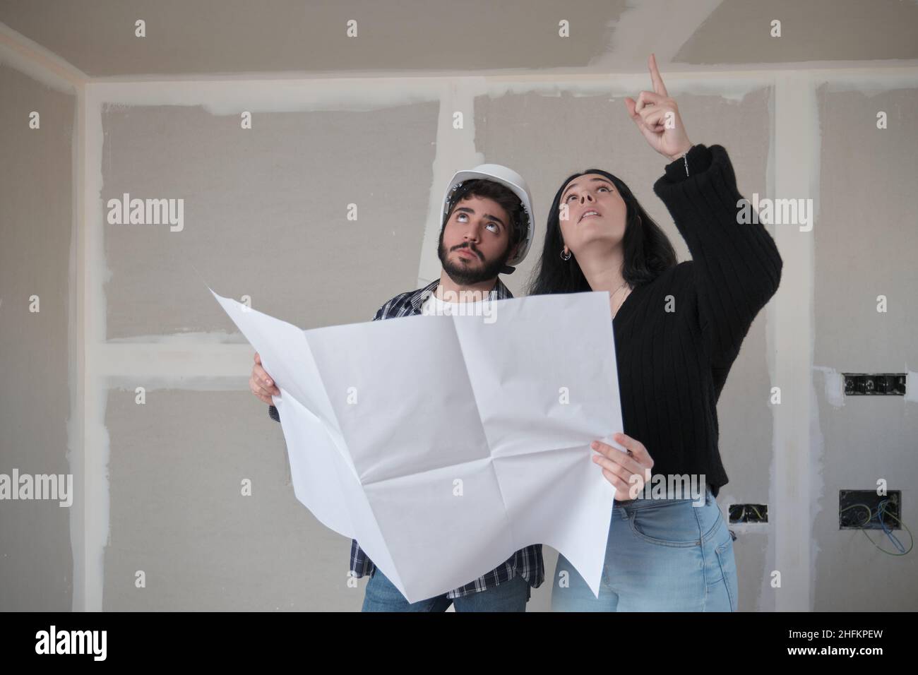Jeune femme demandant à l'architecte au sujet du plafond dans une maison de construction. Banque D'Images