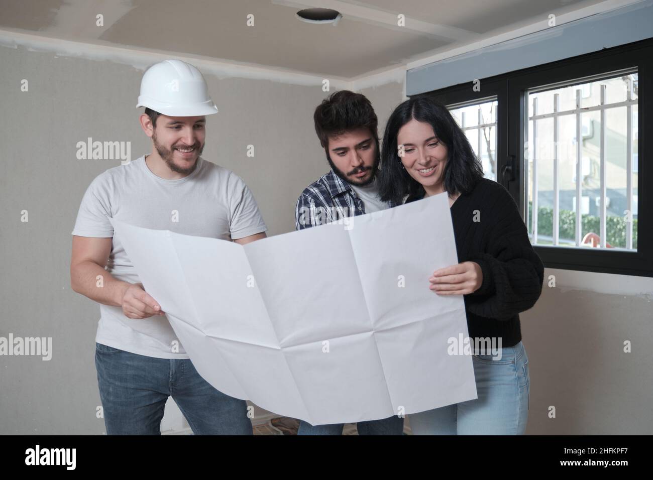 L'architecte montre l'appartement dans des plans de construction à un jeune couple intéressé. Banque D'Images