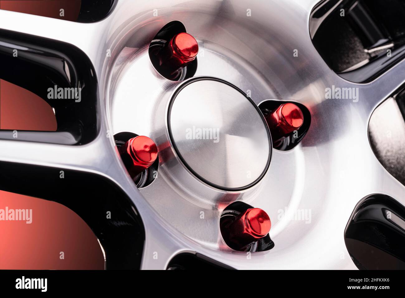 les boulons ou écrous de roue rouges sur les roues en alliage se fragment avec un capuchon.Détail du réglage de la voiture bouchon vide sur fond rouge dégradé. Banque D'Images