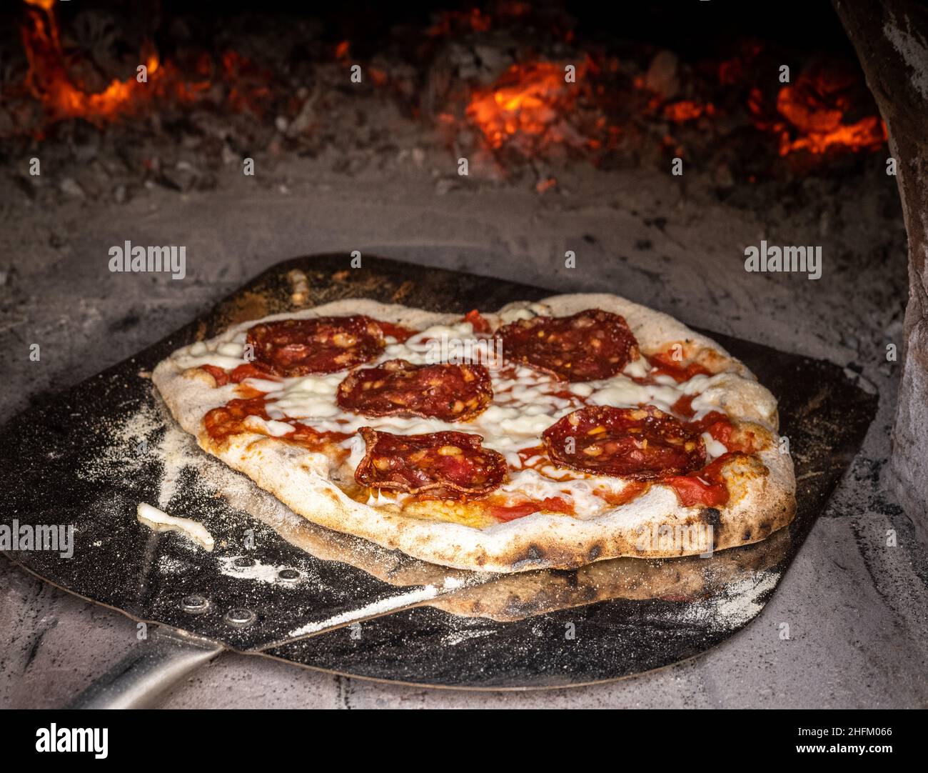 Pizza rustique au feu de bois dans un four à pizza Banque D'Images