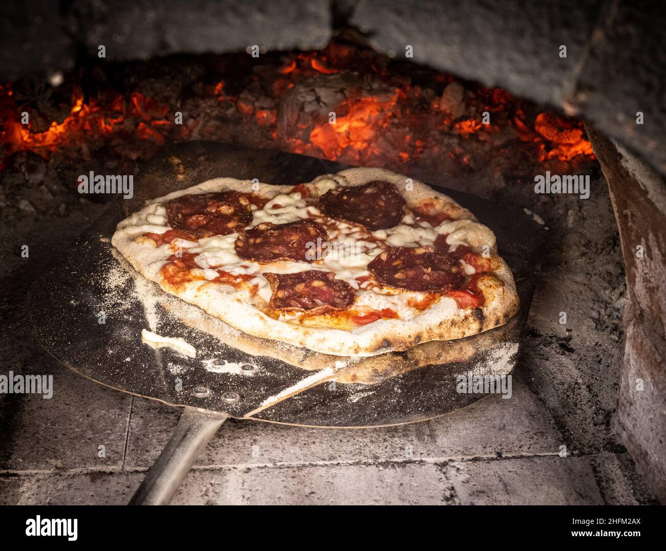 Pizza rustique au feu de bois dans un four à pizza Banque D'Images