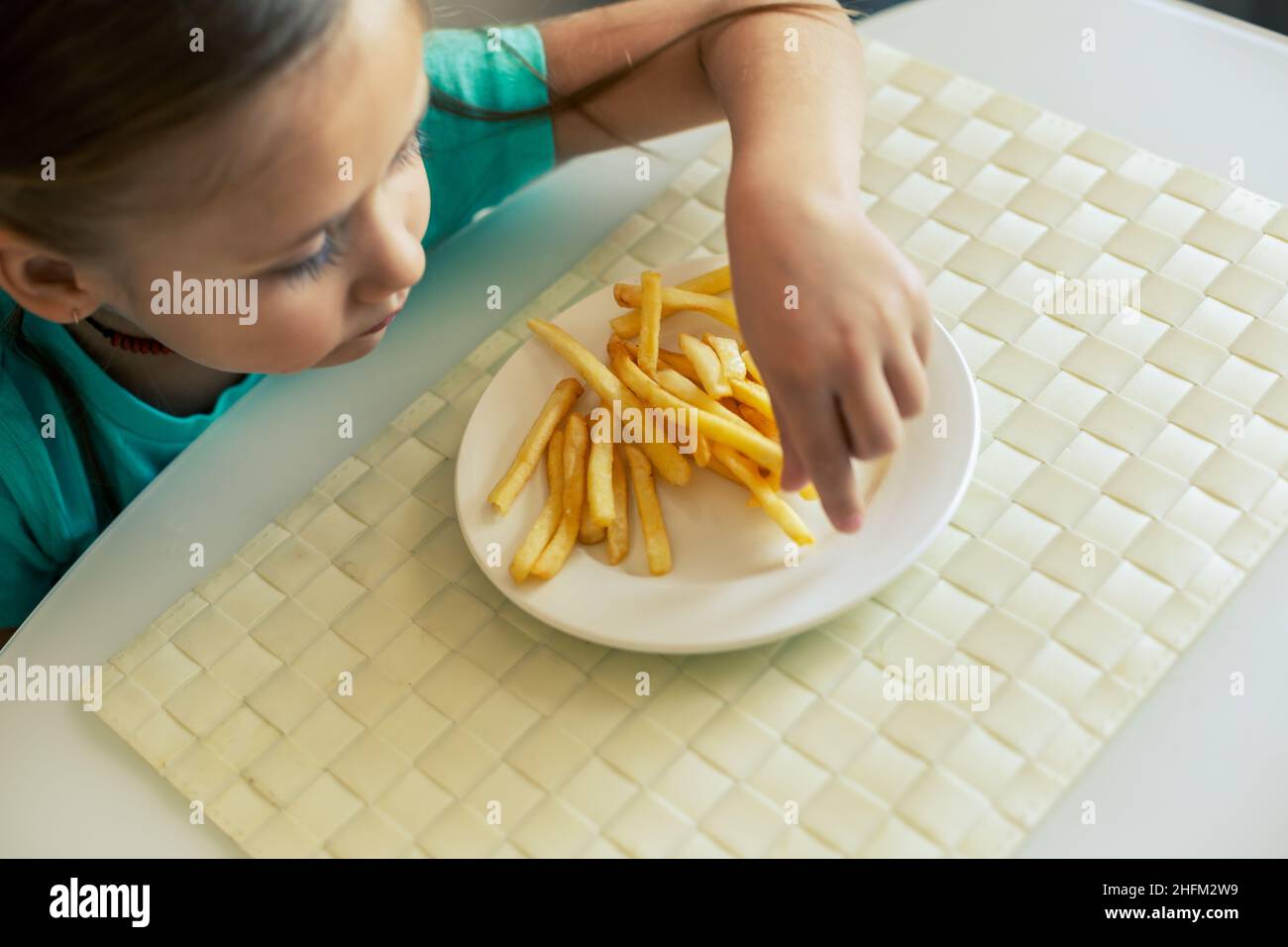 Gros plan d'une petite fille mangeant des frites dans la cuisine Banque D'Images