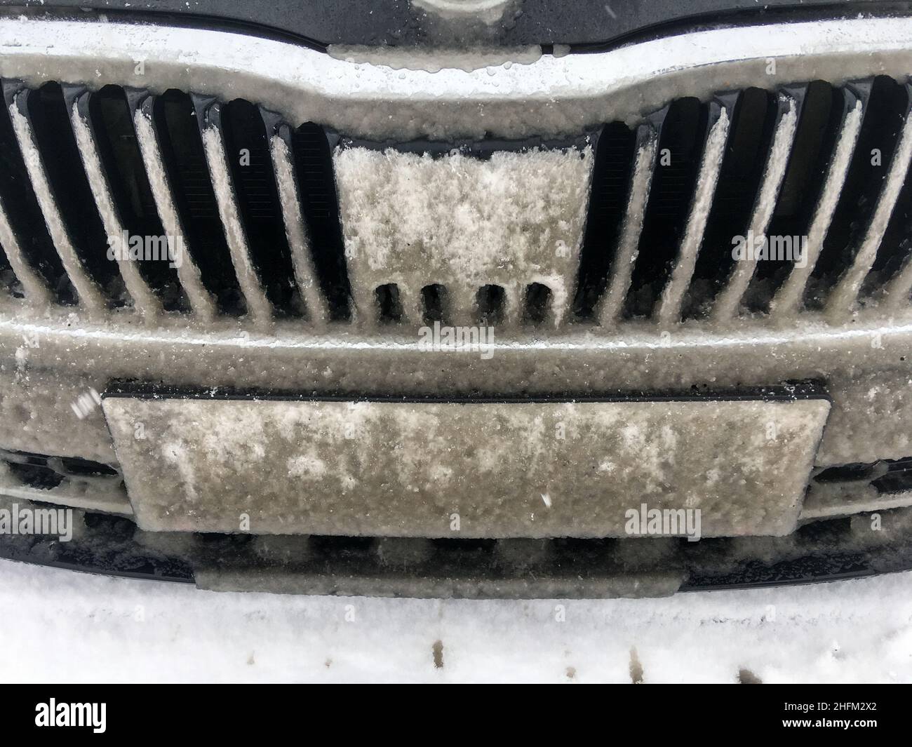 Le détail de la grille du radiateur de voiture entièrement recouvert de neige fondante.Le capteur radar est aveugle.Problème pour les systèmes modernes causé par la météo. Banque D'Images