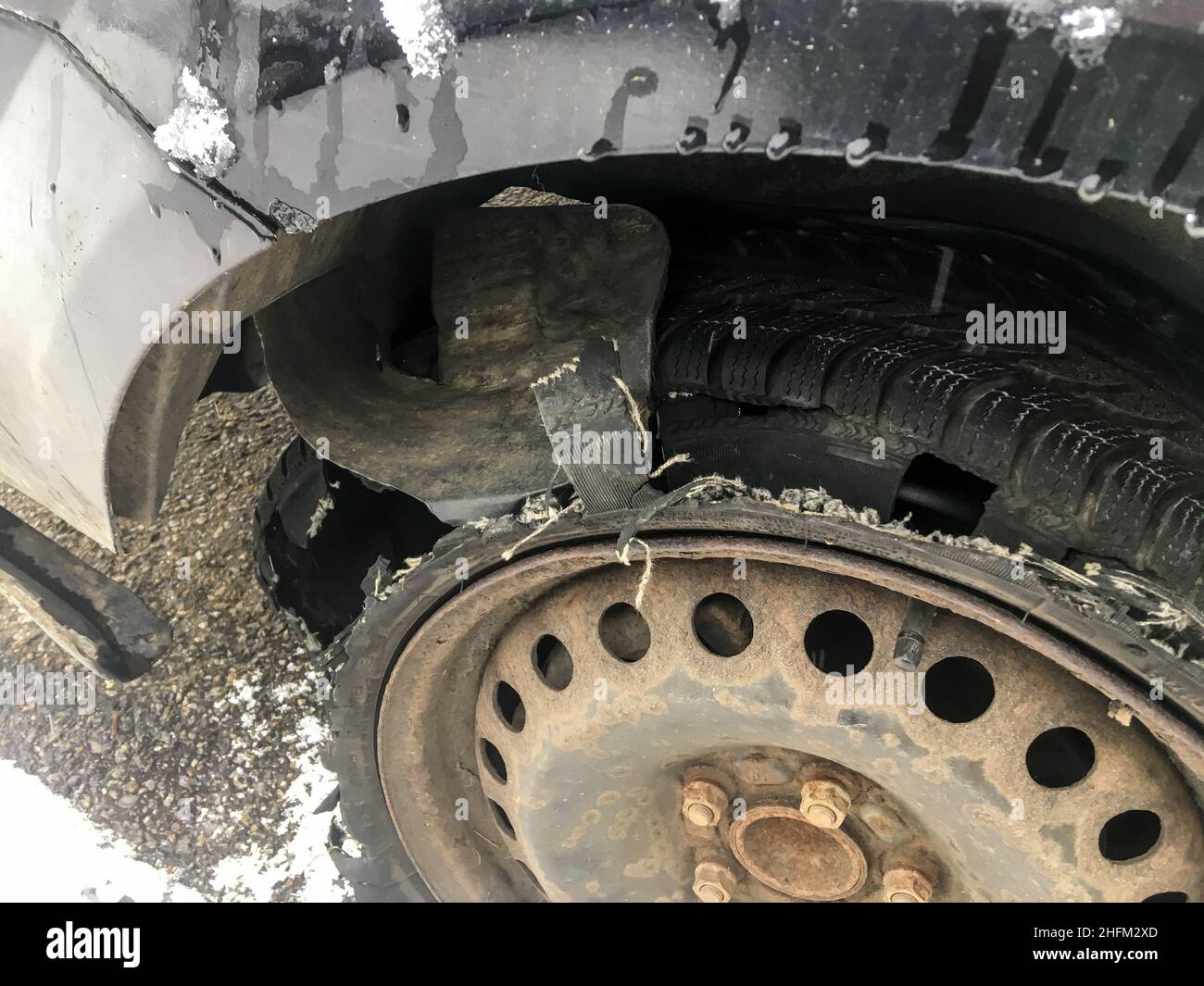 Détail de la roue rouillée avec pneu crevé et détruit sur le véhicule abandonné.Le pneu est complètement cassé avec la bande de roulement séparée. Banque D'Images