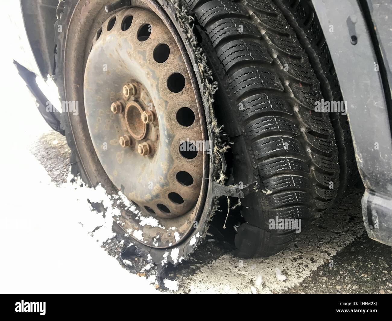 Détail de la roue rouillée avec pneu crevé et détruit sur le véhicule abandonné.Le pneu est complètement cassé avec la bande de roulement séparée. Banque D'Images