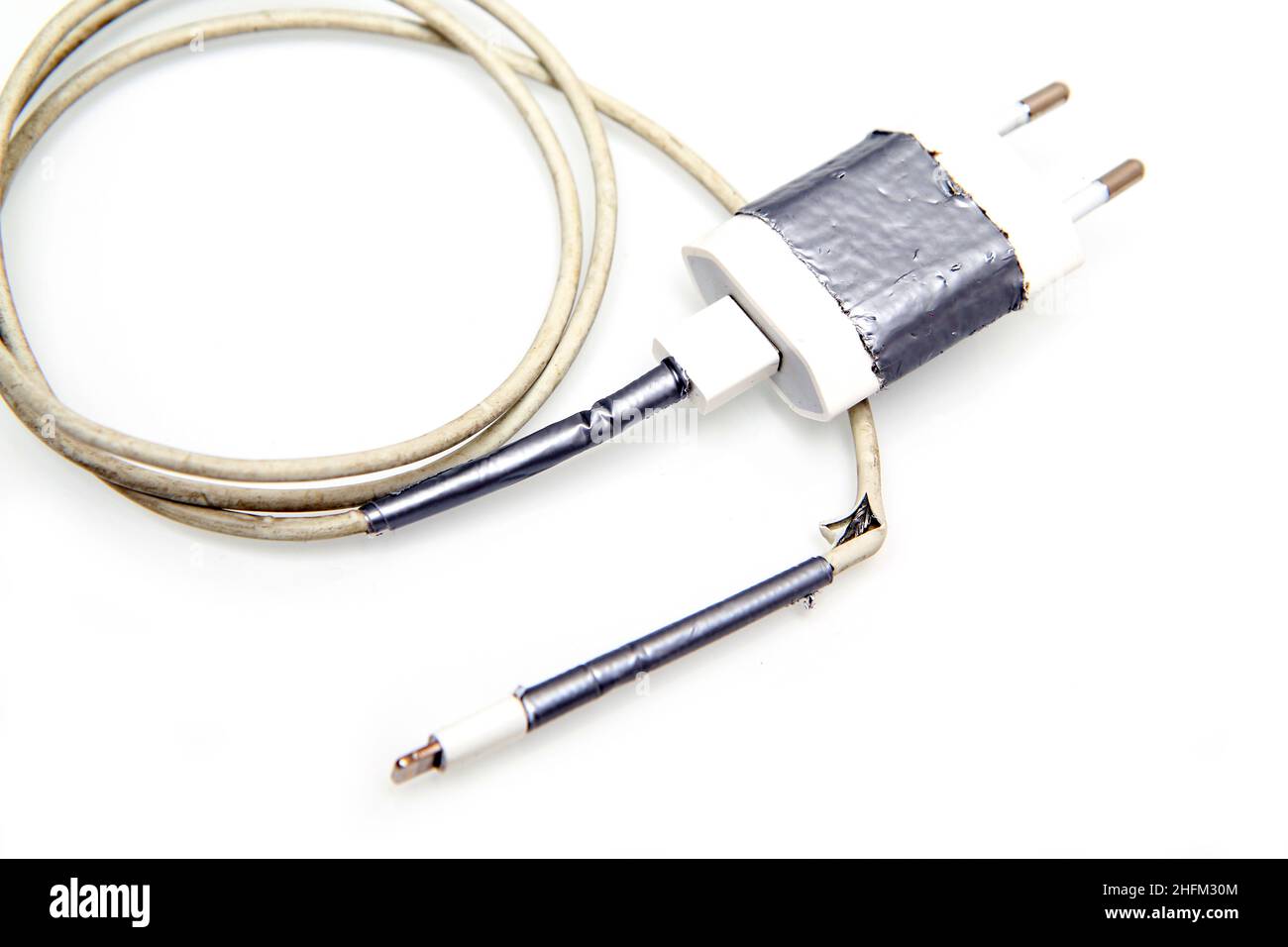 Détail du chargeur des smartphones dont le câble est cassé et effiloché.Déjà une fois fixé par bande, mais cassé à nouveau.Problème type des utilisateurs. Banque D'Images