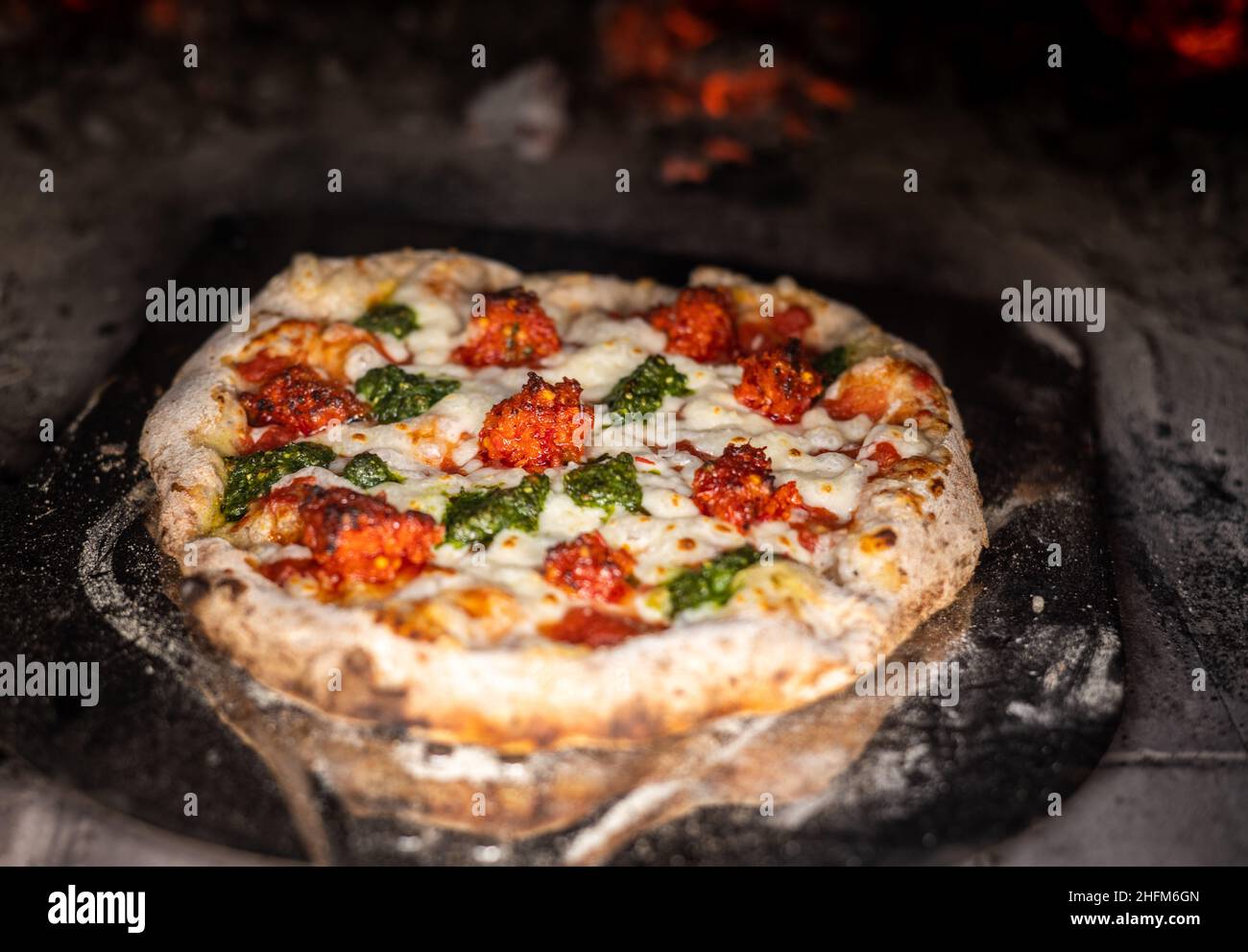 Pizza rustique au feu de bois dans un four à pizza Banque D'Images