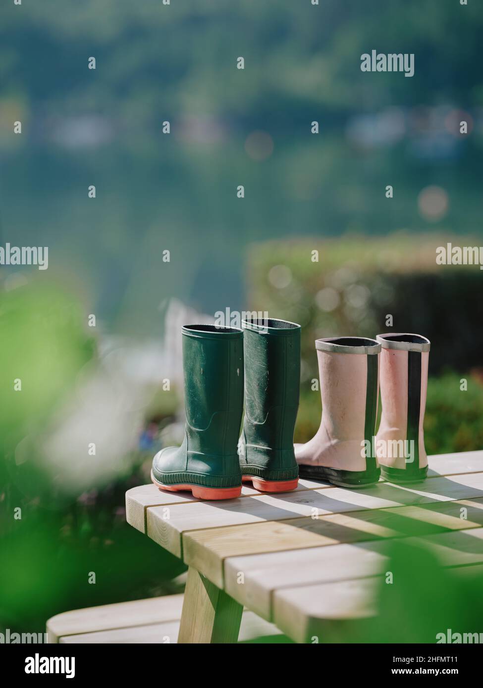 Ses et ses bottes de jardin wellington s'assèchent au soleil du début de l'été sur la table de jardin - rose vert wellies couple retraite de couple style de vie Banque D'Images