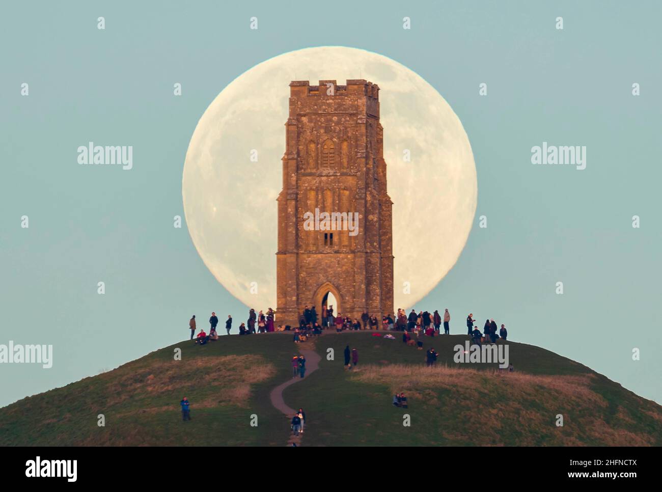 Glastonbury, Somerset, Royaume-Uni.17th janvier 2022.Météo Royaume-Uni.La pleine Lune du Loup s'élève derrière la Tour St Michael's sur Glastonbury Tor dans le Somerset lors d'une soirée froide et claire alors que les gens se tiennent au sommet et la regardent monter.Crédit photo : Graham Hunt/Alamy Live News Banque D'Images