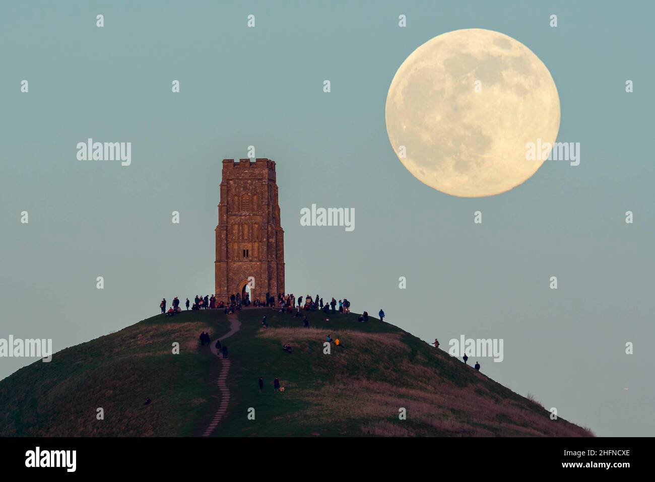 Glastonbury, Somerset, Royaume-Uni.17th janvier 2022.Météo Royaume-Uni.La pleine Lune du Loup s'élève derrière la Tour St Michael's sur Glastonbury Tor dans le Somerset lors d'une soirée froide et claire alors que les gens se tiennent au sommet et la regardent monter.Crédit photo : Graham Hunt/Alamy Live News Banque D'Images