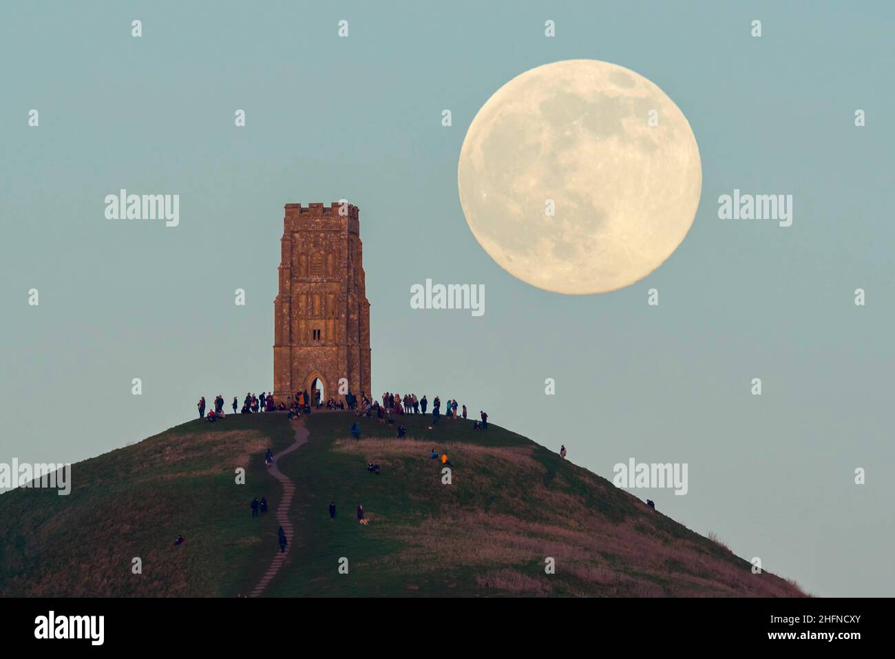 Glastonbury, Somerset, Royaume-Uni.17th janvier 2022.Météo Royaume-Uni.La pleine Lune du Loup s'élève derrière la Tour St Michael's sur Glastonbury Tor dans le Somerset lors d'une soirée froide et claire alors que les gens se tiennent au sommet et la regardent monter.Crédit photo : Graham Hunt/Alamy Live News Banque D'Images