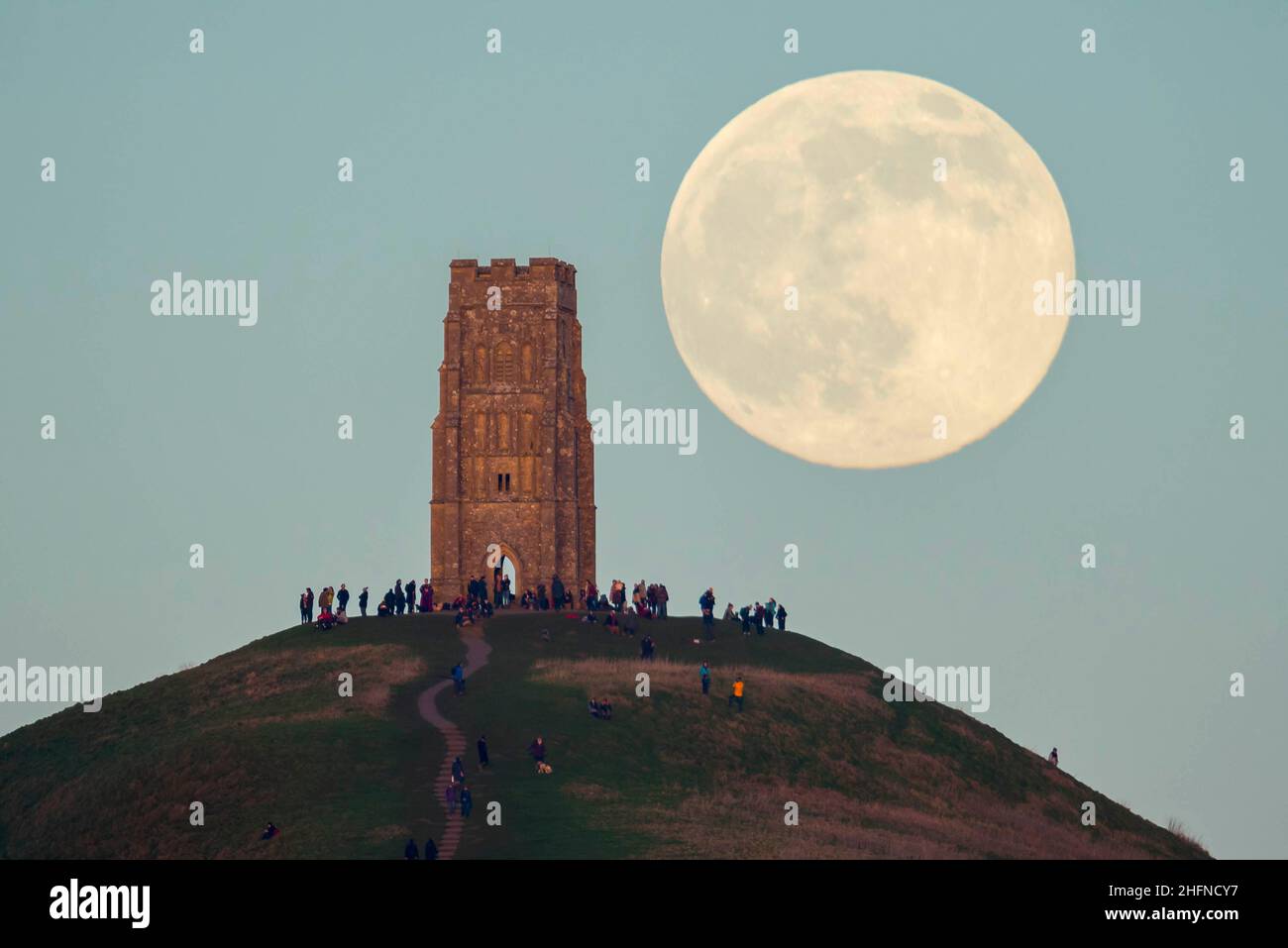 Glastonbury, Somerset, Royaume-Uni.17th janvier 2022.Météo Royaume-Uni.La pleine Lune du Loup s'élève derrière la Tour St Michael's sur Glastonbury Tor dans le Somerset lors d'une soirée froide et claire alors que les gens se tiennent au sommet et la regardent monter.Crédit photo : Graham Hunt/Alamy Live News Banque D'Images