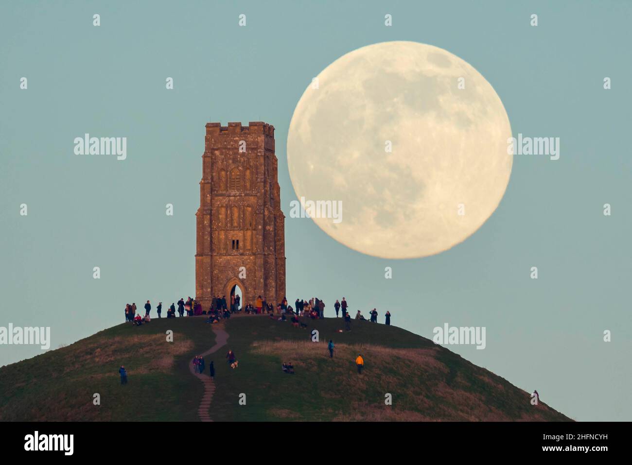 Glastonbury, Somerset, Royaume-Uni.17th janvier 2022.Météo Royaume-Uni.La pleine Lune du Loup s'élève derrière la Tour St Michael's sur Glastonbury Tor dans le Somerset lors d'une soirée froide et claire alors que les gens se tiennent au sommet et la regardent monter.Crédit photo : Graham Hunt/Alamy Live News Banque D'Images
