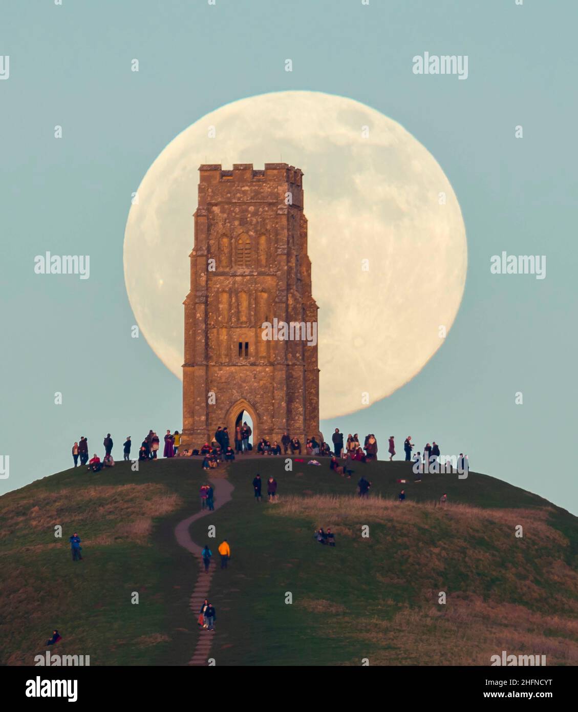 Glastonbury, Somerset, Royaume-Uni.17th janvier 2022.Météo Royaume-Uni.La pleine Lune du Loup s'élève derrière la Tour St Michael's sur Glastonbury Tor dans le Somerset lors d'une soirée froide et claire alors que les gens se tiennent au sommet et la regardent monter.Crédit photo : Graham Hunt/Alamy Live News Banque D'Images