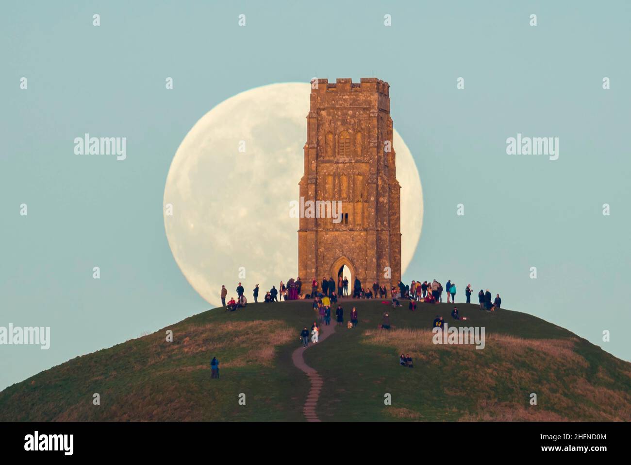 Glastonbury, Somerset, Royaume-Uni.17th janvier 2022.Météo Royaume-Uni.La pleine Lune du Loup s'élève derrière la Tour St Michael's sur Glastonbury Tor dans le Somerset lors d'une soirée froide et claire alors que les gens se tiennent au sommet et la regardent monter.Crédit photo : Graham Hunt/Alamy Live News Banque D'Images