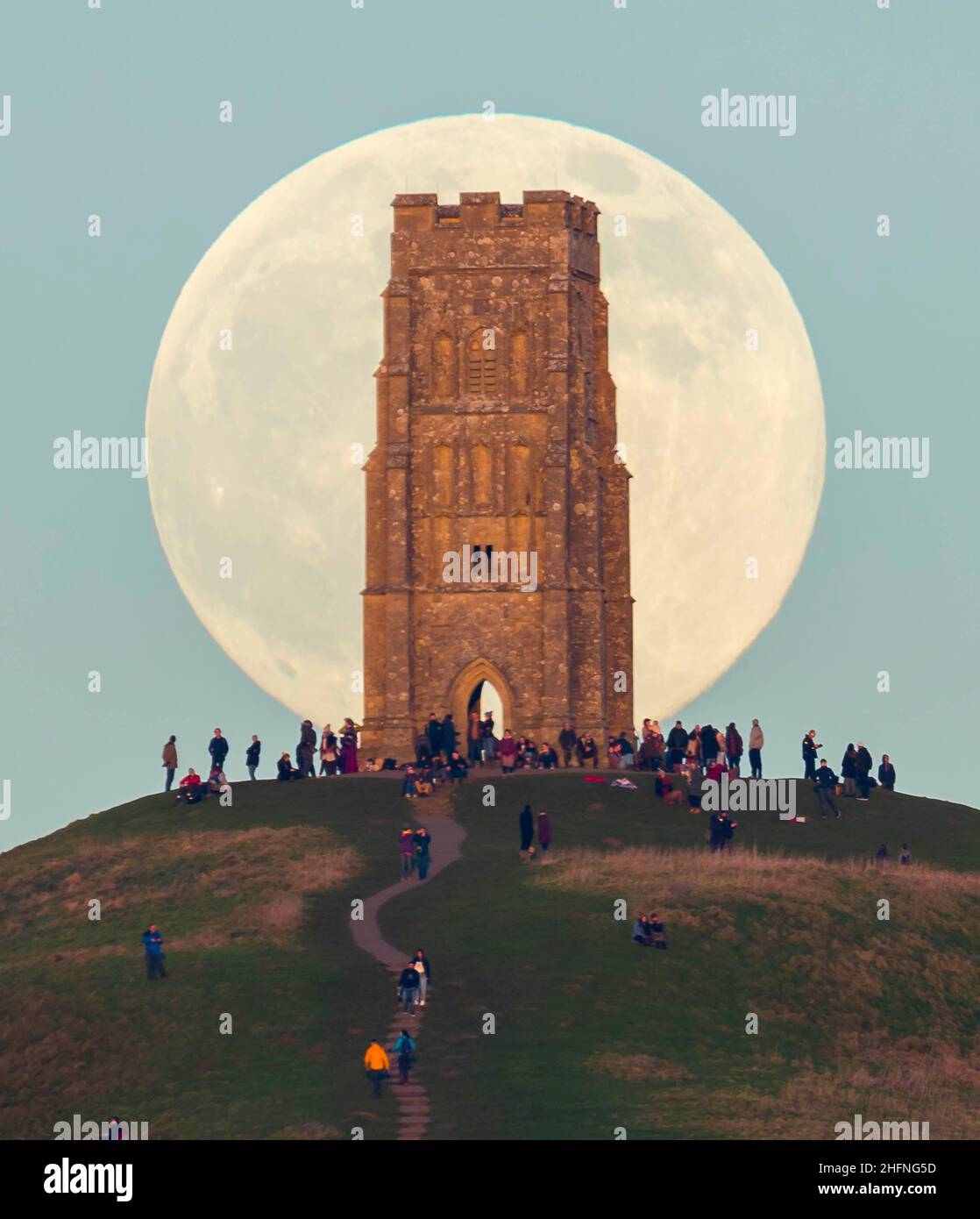 Glastonbury, Somerset, Royaume-Uni.17th janvier 2022.Météo Royaume-Uni.La pleine Lune du Loup s'élève derrière la Tour St Michael's sur Glastonbury Tor dans le Somerset lors d'une soirée froide et claire alors que les gens se tiennent au sommet et la regardent monter.Crédit photo : Graham Hunt/Alamy Live News Banque D'Images